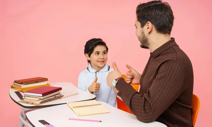 Boy and counselor giving thumbs up at a desk