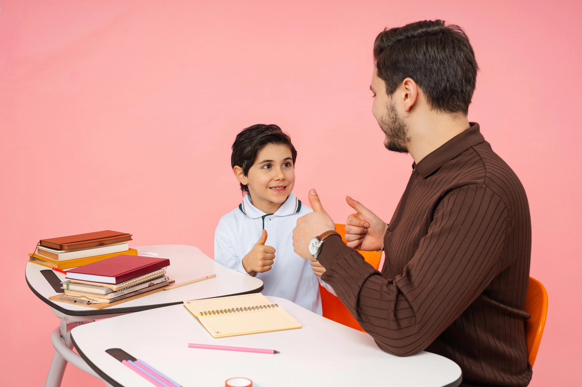 Boy and adult male counselor giving thumbs up to each other at a desk — representing positive behavioral support and the goals of a behavior intervention plan