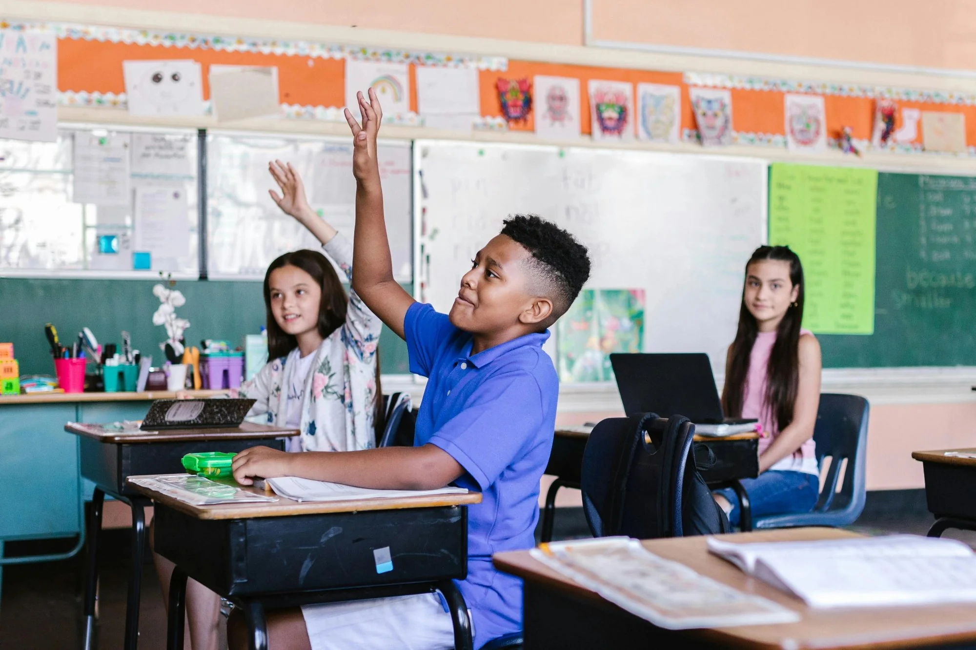 Niño confiado levantando la mano en clase para pedir ayuda al maestro