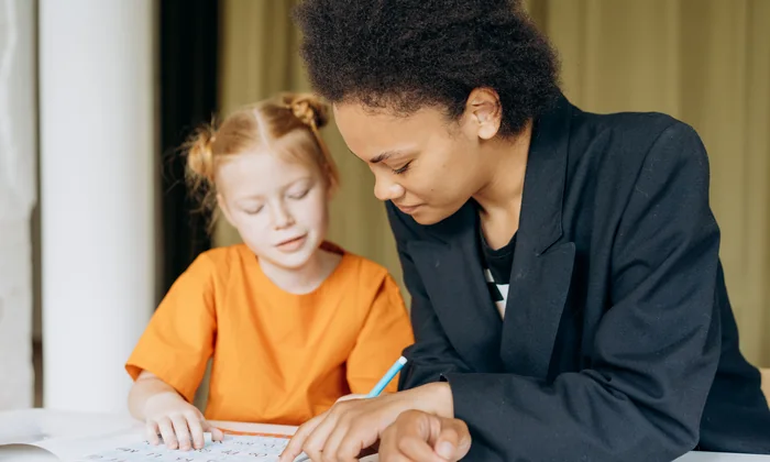 Paraprofessional sitting beside a student and supporting her with classwork