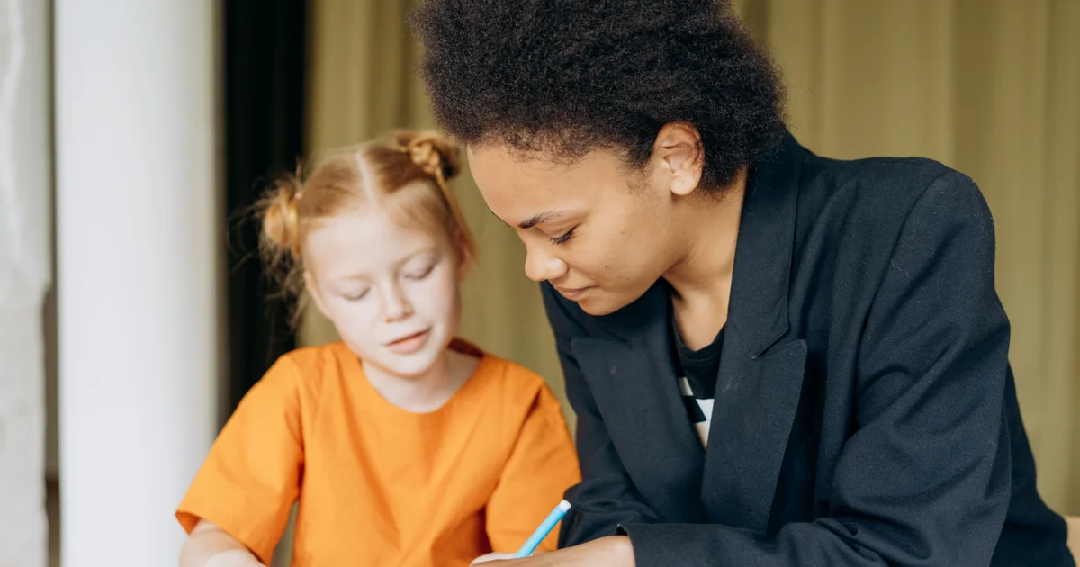 Paraprofessional sitting beside a student and supporting her with classwork