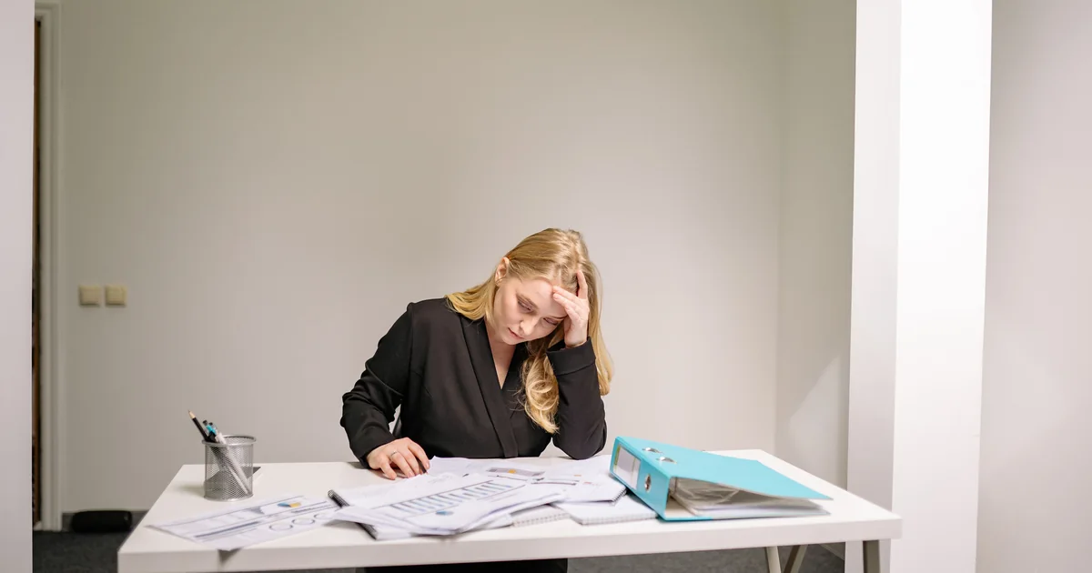 Una madre sentada ante una mesa llena de documentos, decidiendo qué vía tomar