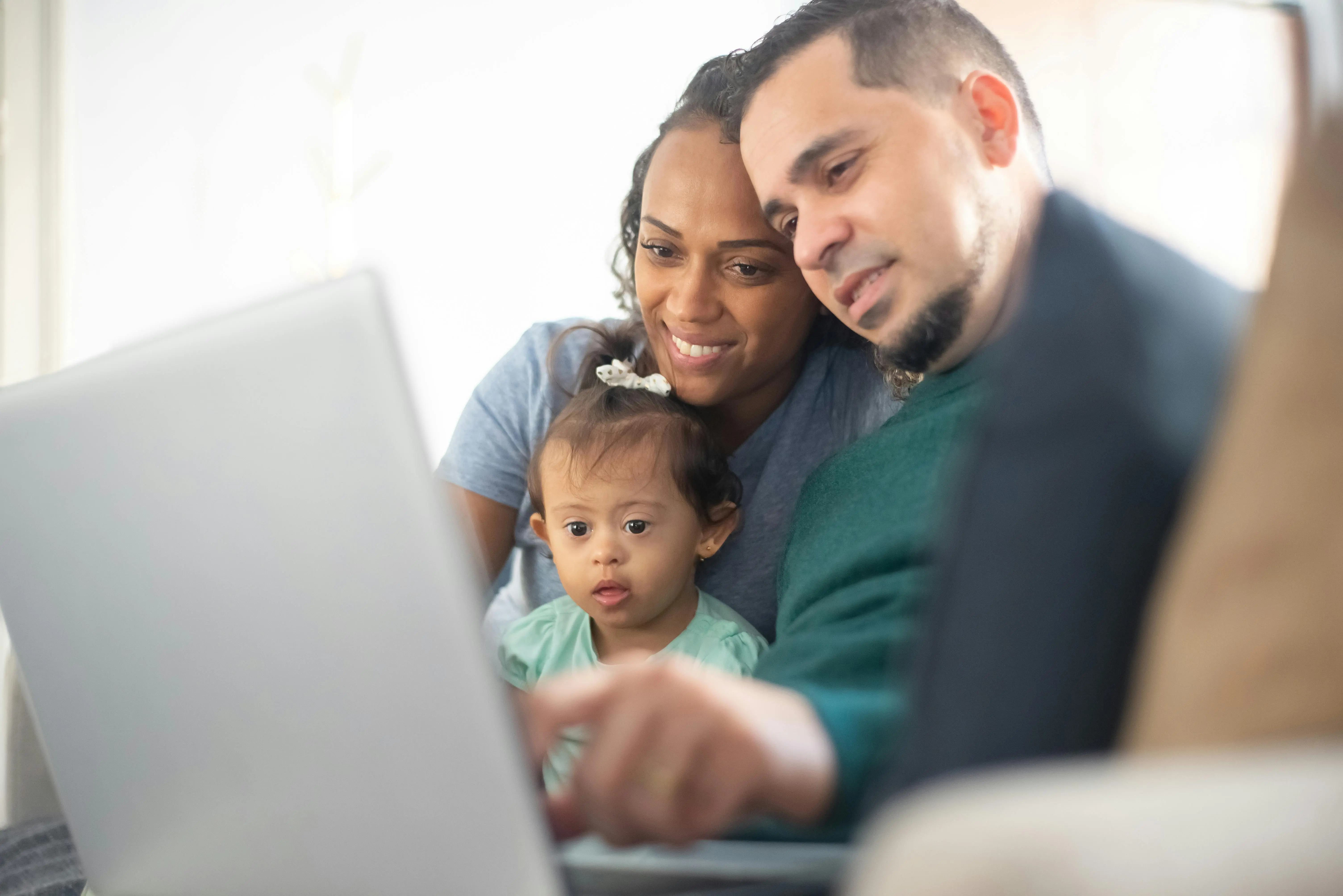 Family with child with Down syndrome smiling at IEP Desk on laptop